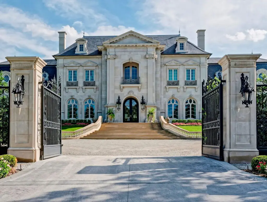 A large white mansion with two gates open.