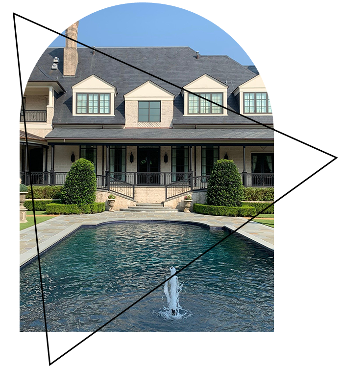 A fountain in front of a large house.