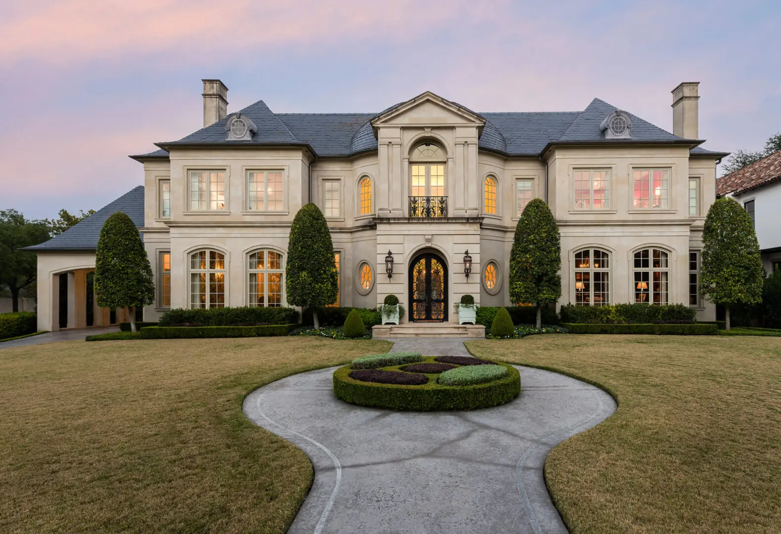 A large mansion with a circular driveway in front of it.